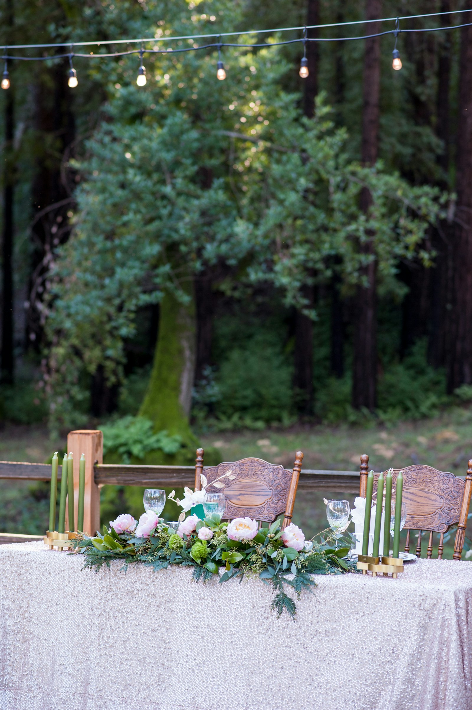 Elegant outdoor reception table with blush flowers, greenery, and string lights